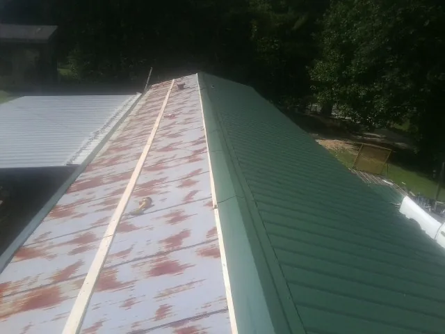 Old rusted panels beside newly installed green metal roofing — Wind Damage Roof Repair by Roofing Brothers in Summertown