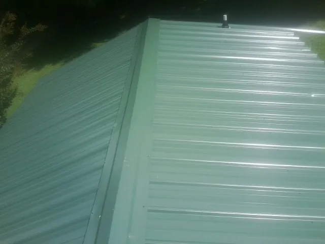 New green metal panels meeting at the ridge of a roof — Flat Roof Repair work by our crew in Summertown