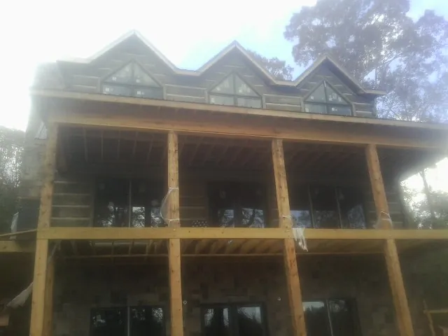 Dormers and porch framing on a large log home under construction — Roof Coating work by our crew in Summertown