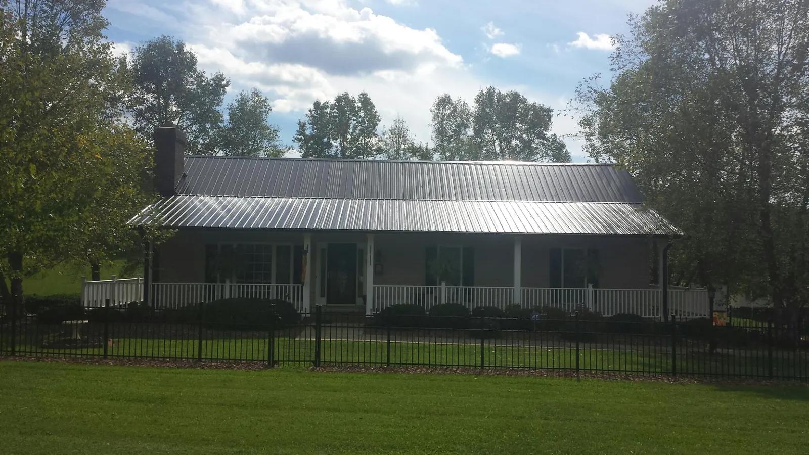 Gray metal roof on a brick ranch with a full width front porch — Gutter Guard Installation work by our crew in Summertown