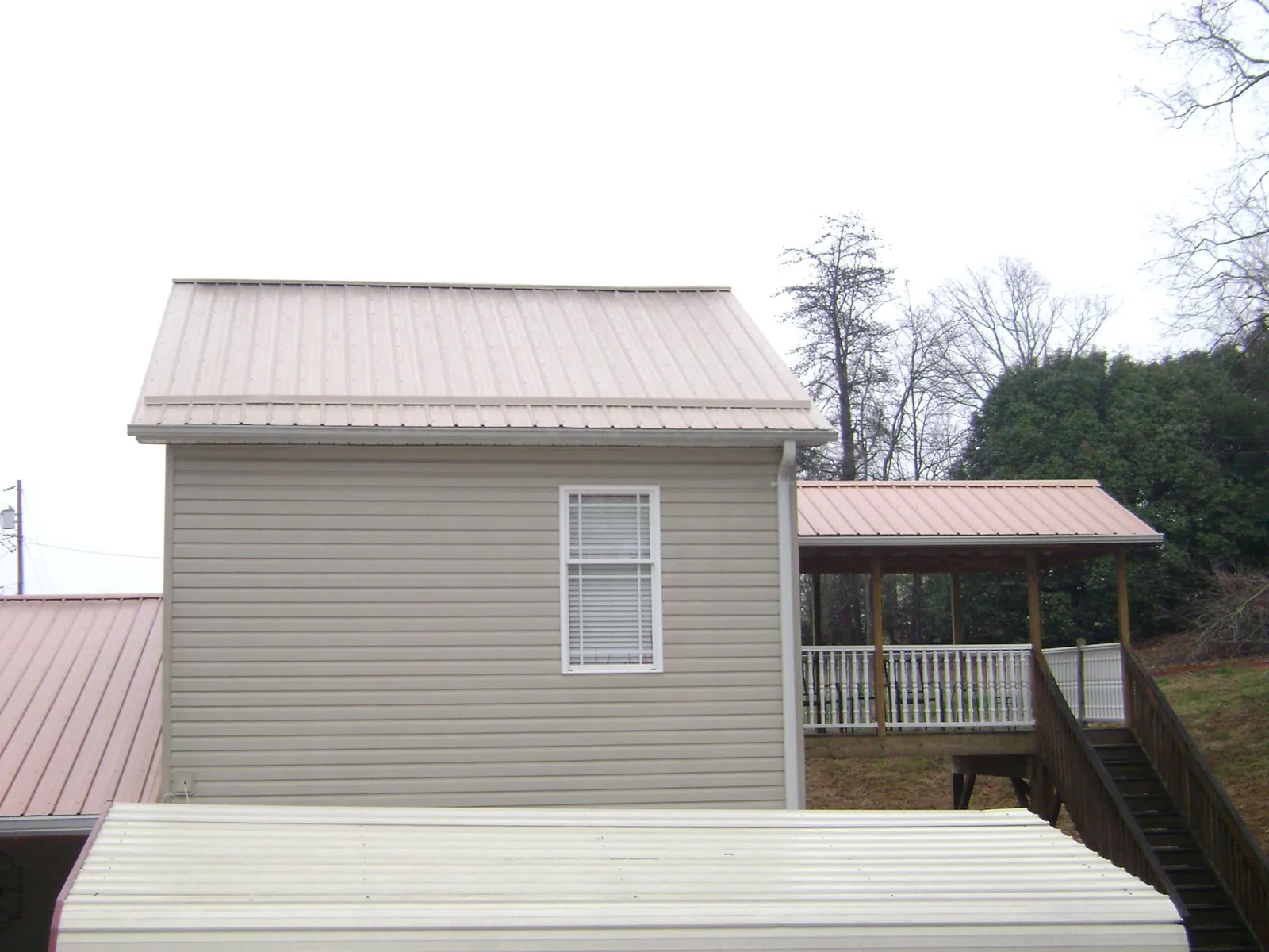 Tan metal roofs on a two story addition and attached porch, from a Roof Replacement job in Summertown