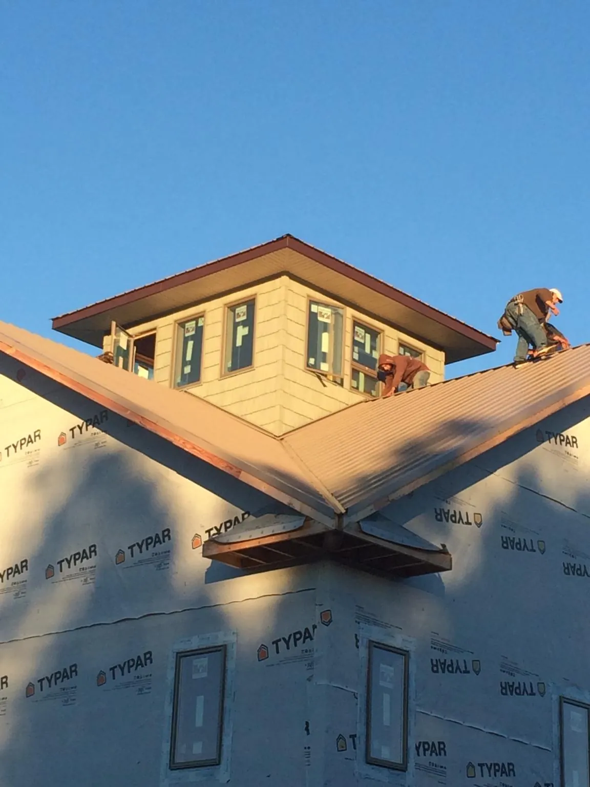 Roofers working around a rooftop cupola on a new metal roof at sunset — Roof Waterproofing in Summertown by Roofing Brothers